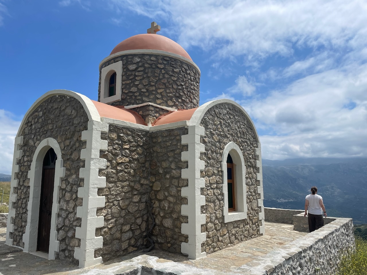 A small stone chapel with a terracotta dome on a ridge above the valley