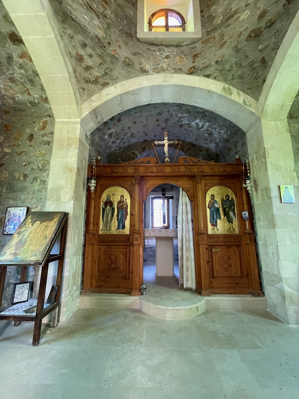 Stone arch and carved wooden iconostasis inside a Meronas church