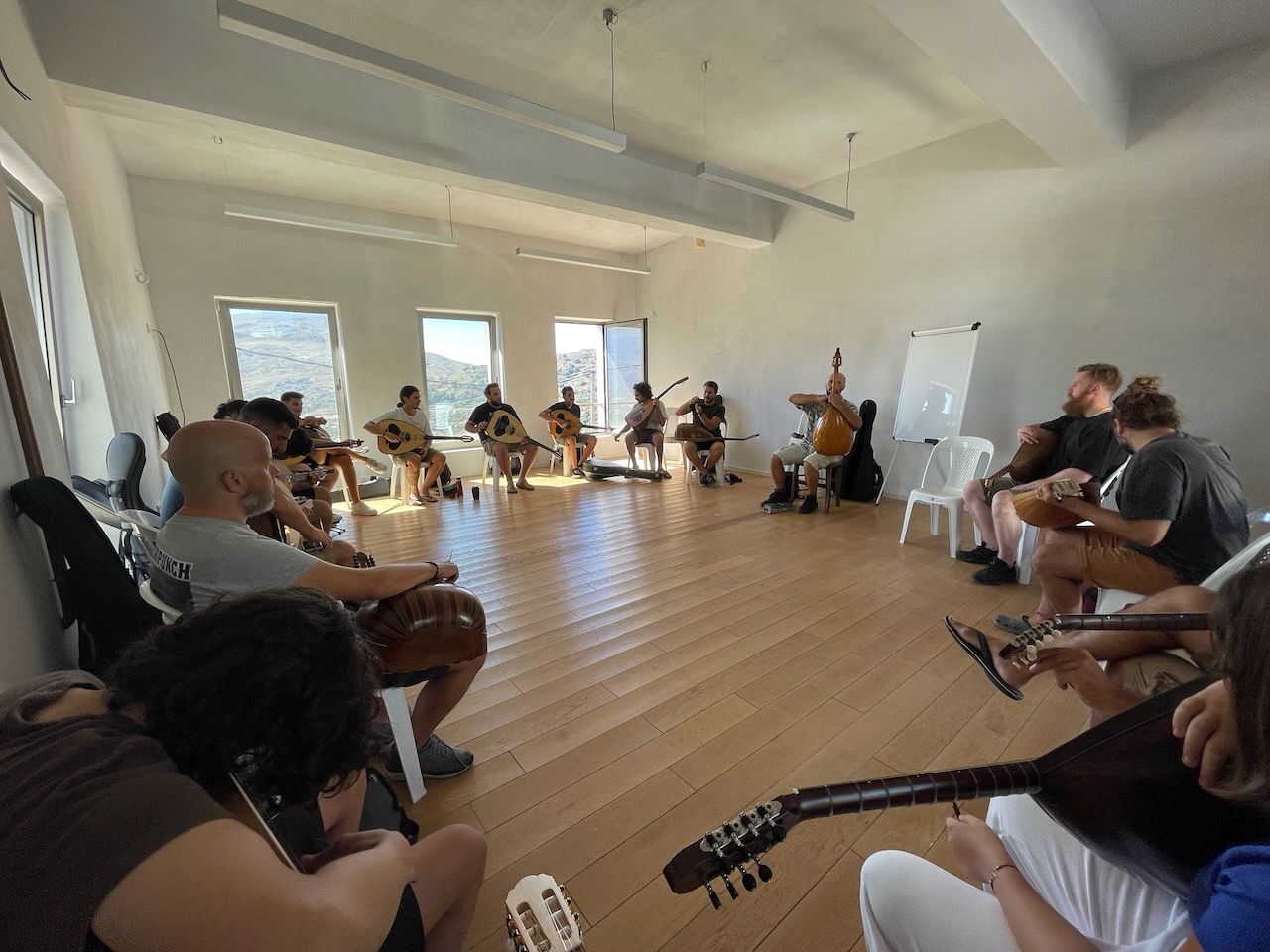 Musicians sitting in a circle playing Cretan lyra and lute at the Meronas Music Workshop